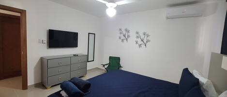 A bedroom with a bed, a dresser, a TV, a ceiling fan, and wall decorations.