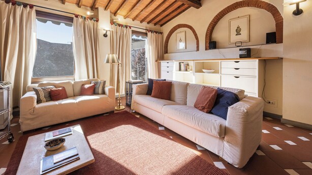 Een woonkamer met een bank, een bijzettafeltje en een boekenplank.