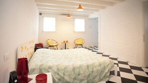 Een kamer met een bed, twee stoelen, een klein tafeltje en een zwart-wit geruite vloer.