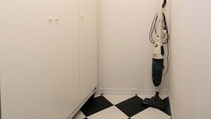 Een kleine kamer met een zwart-witte vloer, witte muren en een witte garderobe.