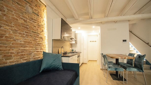 A cozy living area with a brick wall, a sofa, and a dining table with chairs.