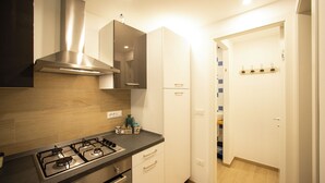 A modern kitchen with a gas stove, stainless steel range hood, and white cabinetry.