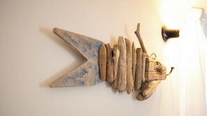 Eine an der Wand befestigte Holzskulptur, die einen Fisch mit einer großen Pfeilspitze an der Seite darstellt.