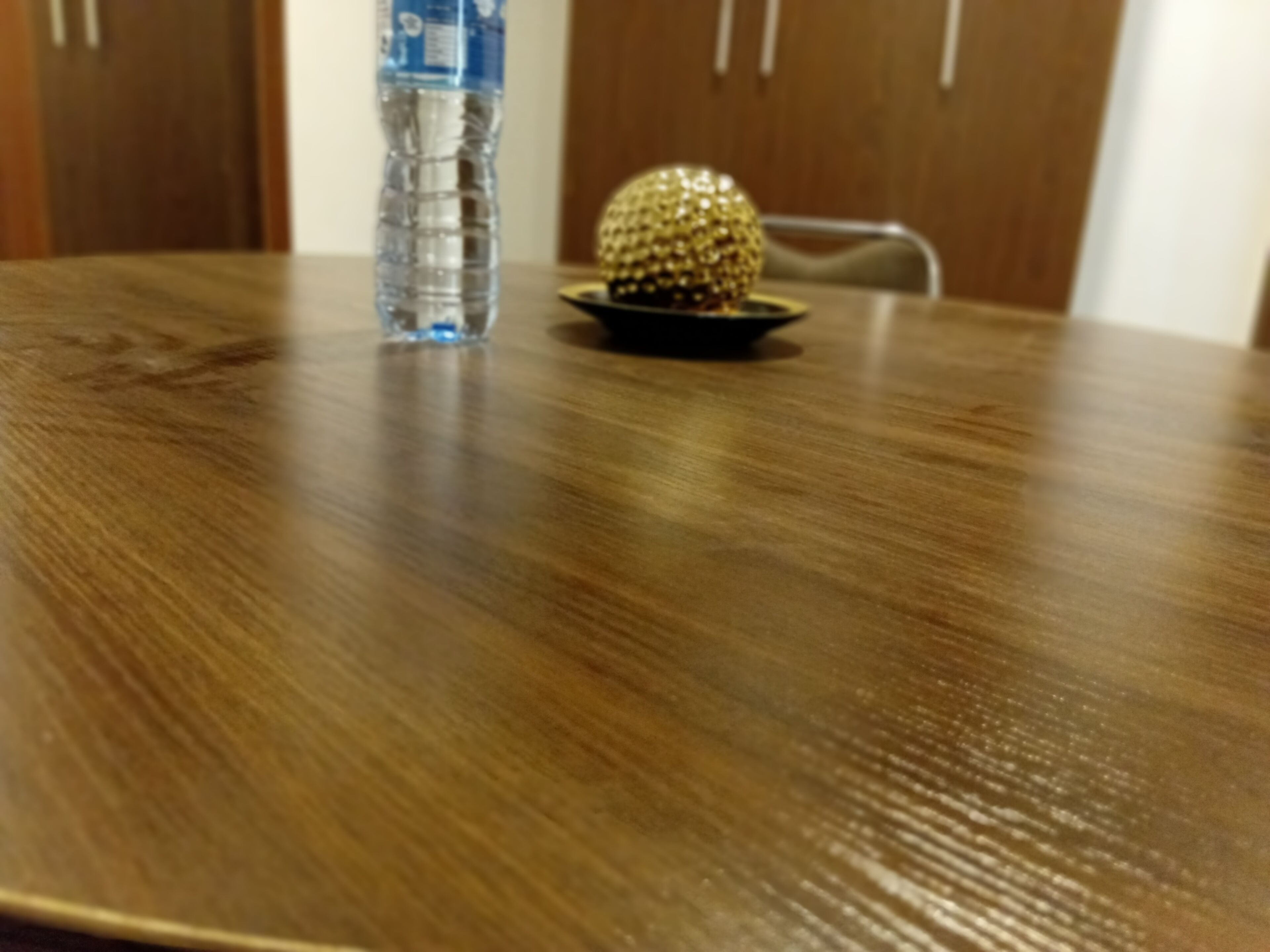 A wooden table with a water bottle and a decorative object on it.