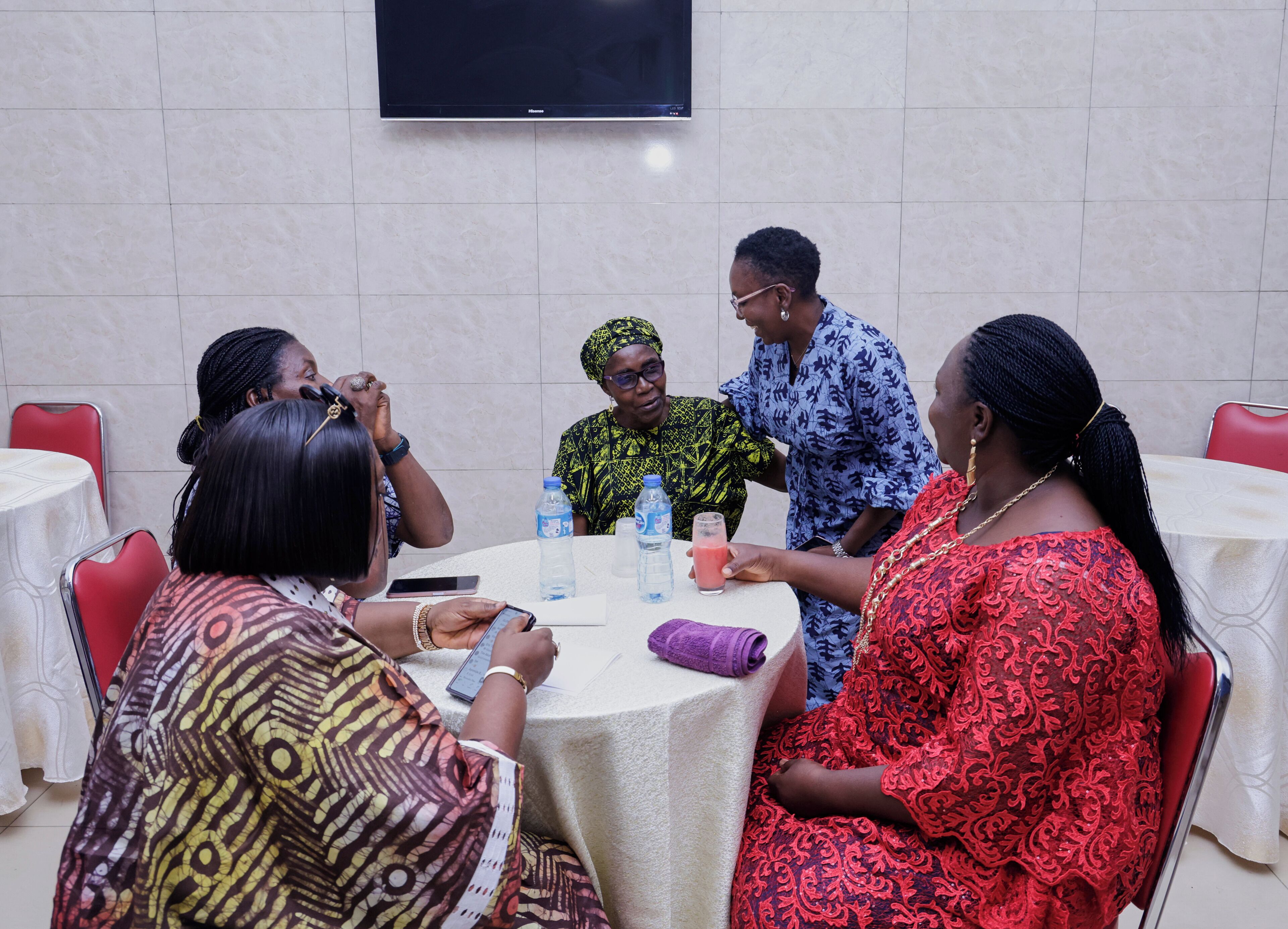 Un grupo de personas sentadas alrededor de una mesa redonda con mantel blanco, conversando.