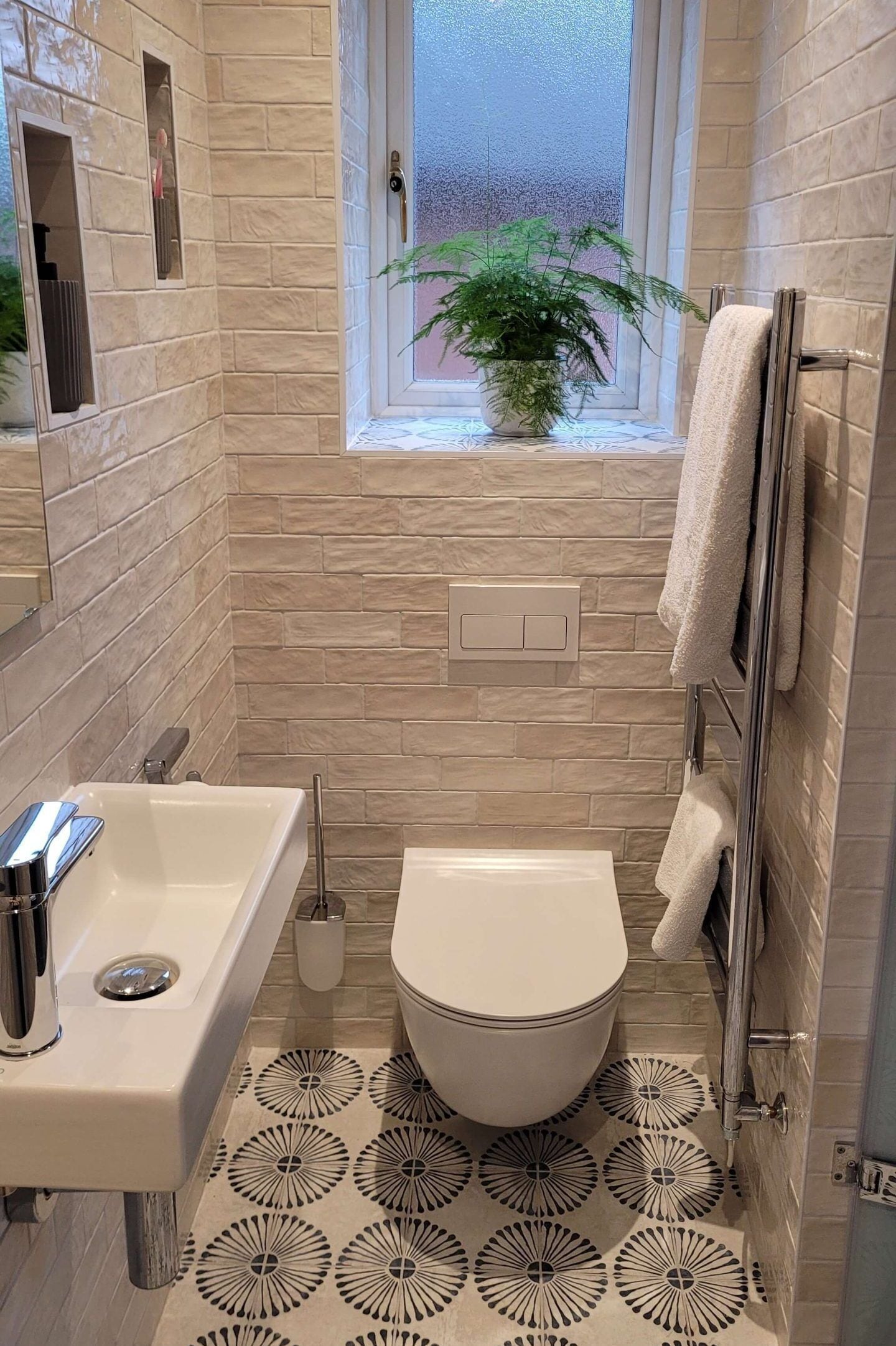 A bathroom with a toilet, sink, and a window with a plant.