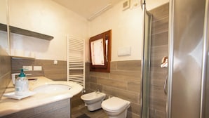 Un bagno moderno con lavandino, bidet, wc e box doccia in vetro.