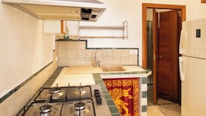 Una cucina con piano cottura a gas, lavello e frigorifero.