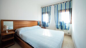 Una camera da letto con un letto in legno, un comodino, una lampada e una finestra con tende.