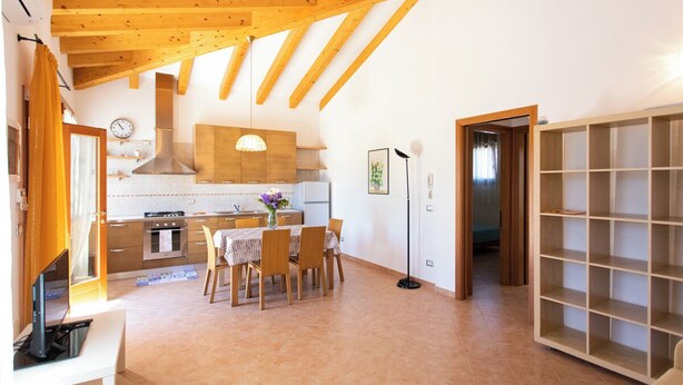 Une cuisine moderne avec des poutres en bois, un coin repas avec une table et des chaises, et une grande bibliothèque.
