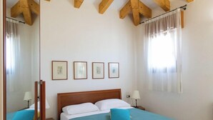 Une chambre avec deux lits, des poutres en bois au plafond et des tableaux encadrés accrochés au mur.