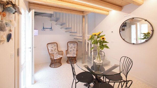 Un coin repas avec une table en verre, des chaises en osier et un vase rempli de tournesols.