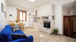 A compact living space with a kitchenette, a dining area, and a sofa. - Dimora Stella  -apeliving- Pellestrina Ve (Venice)