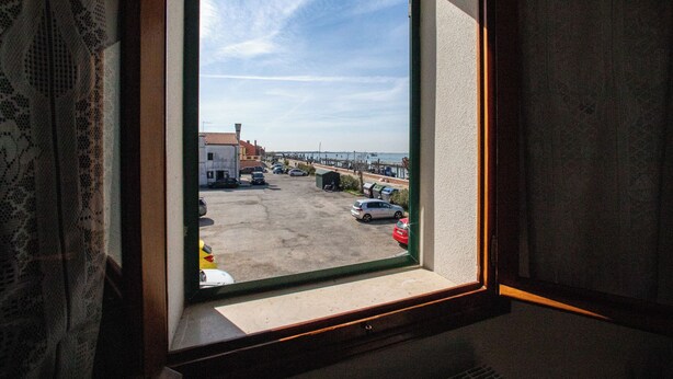 A window view of a parking lot with cars and a building in the background.