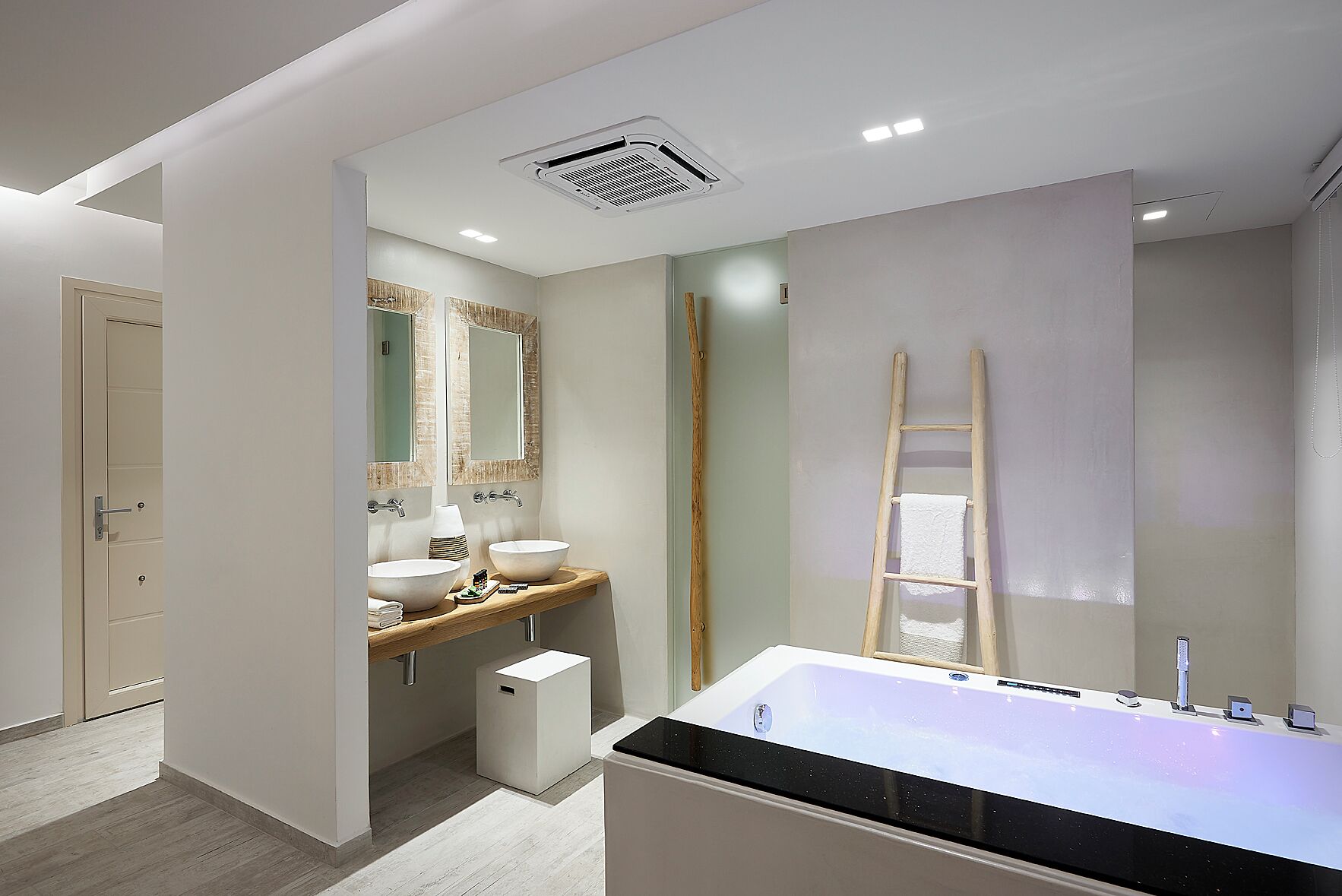 A modern bathroom with a large bathtub, two sinks, and a mirror.