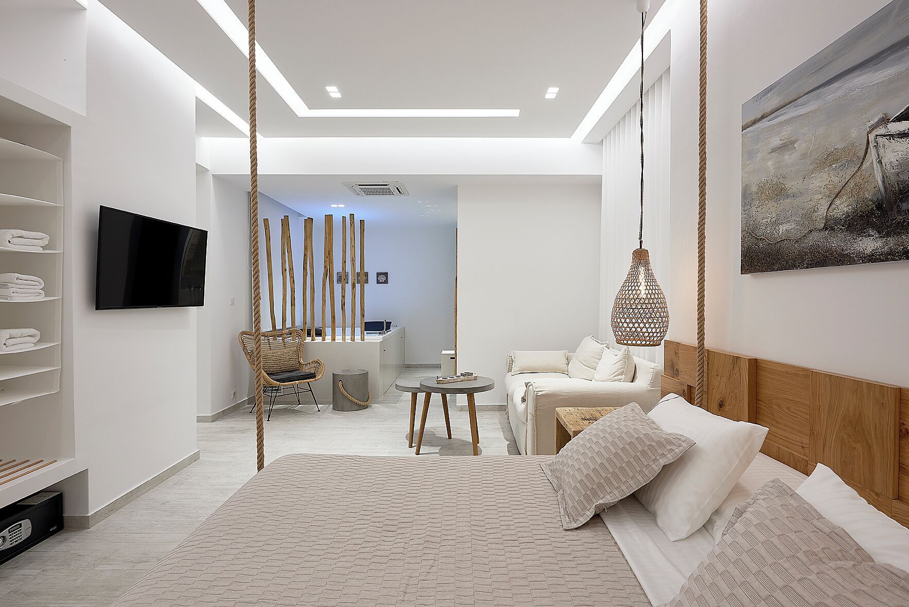 Ein modernes Schlafzimmer mit Bett, Sofa, Fernseher und Schreibtisch.