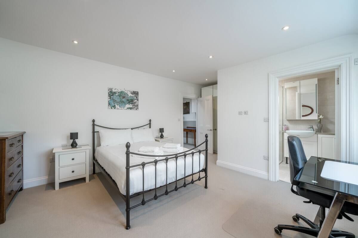 Une chambre à coucher comprenant un lit, des tables de chevet, un bureau et une chaise.