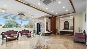 Un'ampia hall con pavimento in marmo, zone salotto e una reception.