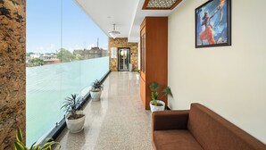 Una hall d'albergo moderna con vista sulla città, una reception e un divano marrone.