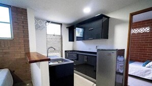 A compact kitchen with a sink, cabinets, and a refrigerator. - Apartahotel Montes  (Medellin)