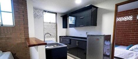 A compact kitchen with a sink, cabinets, and a refrigerator.