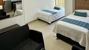 A hotel room with two single beds, a sofa, a TV, and a kitchenette. - Apartahotel Montes  (Medellin)