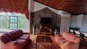 Ein Wohnzimmer mit Kamin aus Stein, zwei Sofas, einem Couchtisch und einem Fernseher.
