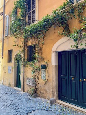 A building with a green door and a number 69 sign, featuring a cobblestone street and a blue door. - Charming 1-bedroom apartment with private terrace, WiFi, AC in old town of Roma (Roma)