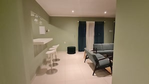 A modern living room with a grey sofa, a white coffee table, and a small black trash bin.