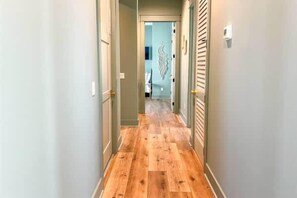 Un couloir doté d’un plancher en bois et de murs aux couleurs claires.