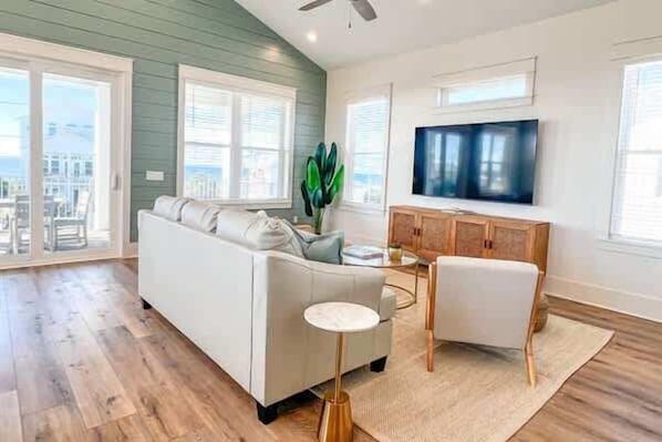Una sala de estar moderna con un sofá, una mesa de centro y un televisor sobre un mueble de madera.