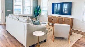 A living room with a sofa, a chair, a coffee table, and a TV on the wall.