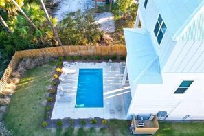 Una propiedad residencial con piscina, patio cercado y una casa blanca.