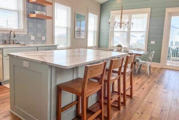 Una cocina con una isla central, sillas de madera y vistas al exterior.