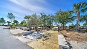 A landscaped area with a paved walkway, wooden deck, and various plants.
