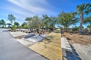 Un área ajardinada con un sendero pavimentado, una terraza de madera y diversas plantas.