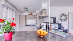 A modern kitchen with a marble countertop, a red potted plant, and a fruit bowl. - L'Orée du Cap - Climatisé proche plage (Six-Fours-les-Plages)