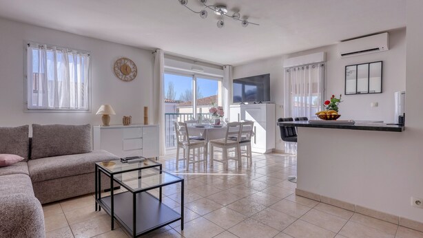 A modern living room with a sofa, a glass coffee table, and a dining area with chairs and a table. - L'Orée du Cap - Climatisé proche plage (Six-Fours-les-Plages)
