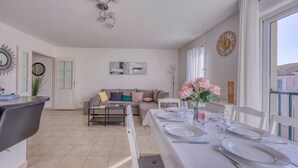 A dining area with a long table set for two, a sofa, and a dining chair. - L'Orée du Cap - Climatisé proche plage (Six-Fours-les-Plages)