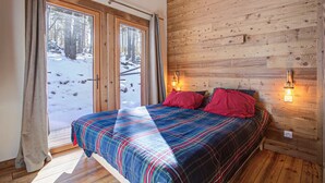 Ein Schlafzimmer mit einem großen Bett, Holzwänden und einem Fenster mit Vorhängen.