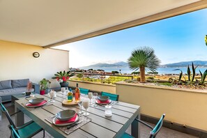 Uma sala de jantar com mesa posta para quatro, com vista panorâmica para a costa.
