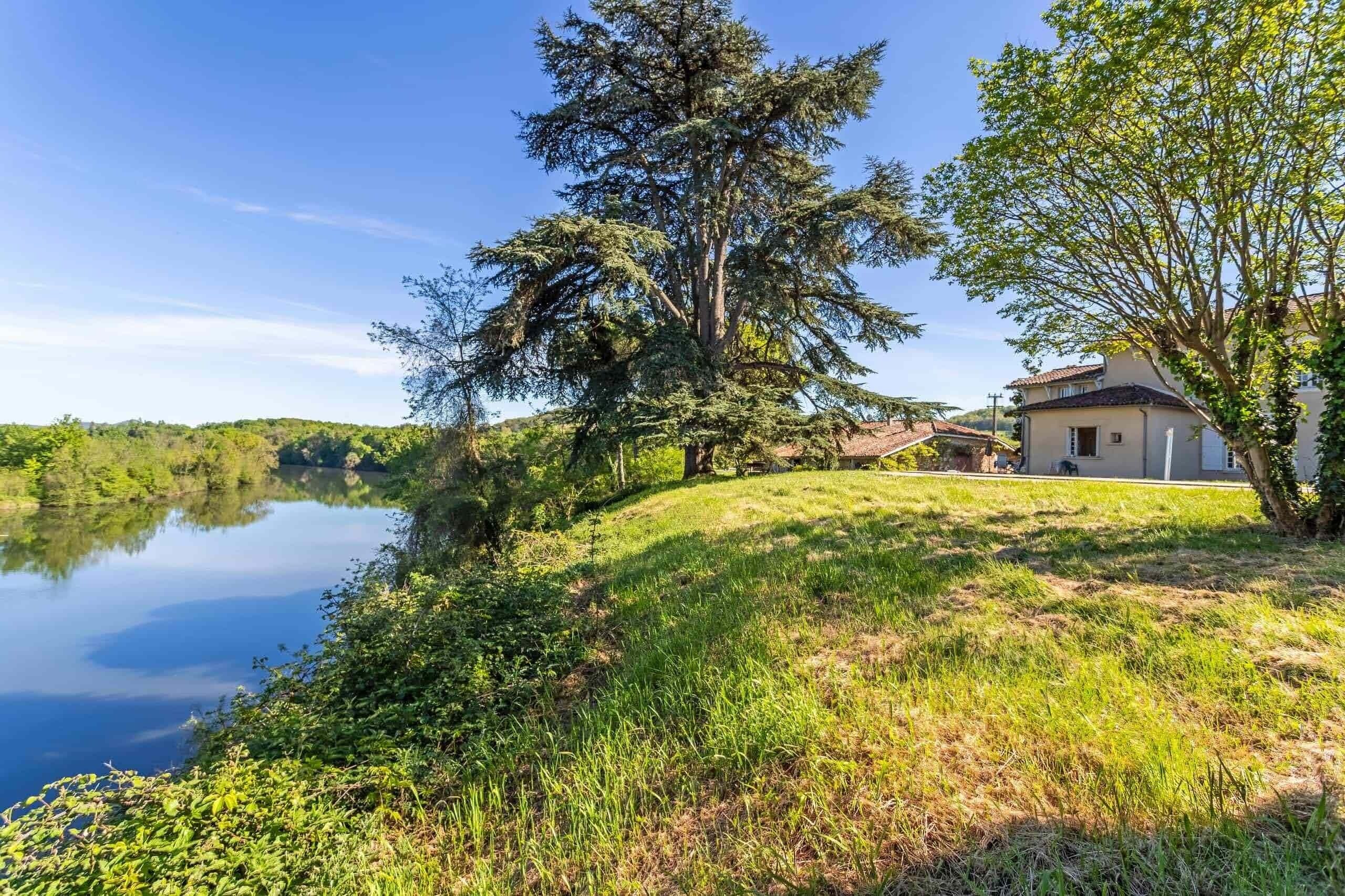A house by a lake with a grassy area and trees.