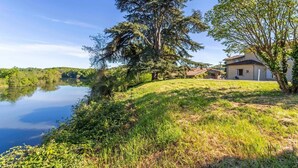 Una casa vicino a un lago, con un'area verde e alberi.