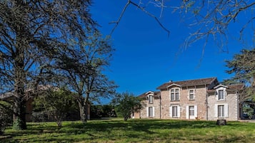 A two-story stone building with a symmetrical facade, multiple windows, and a well-maintained lawn in front.