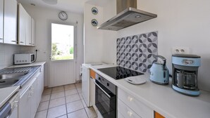 Una cocina moderna con armarios blancos, un microondas, una estufa, un hervidor y una cafetera.