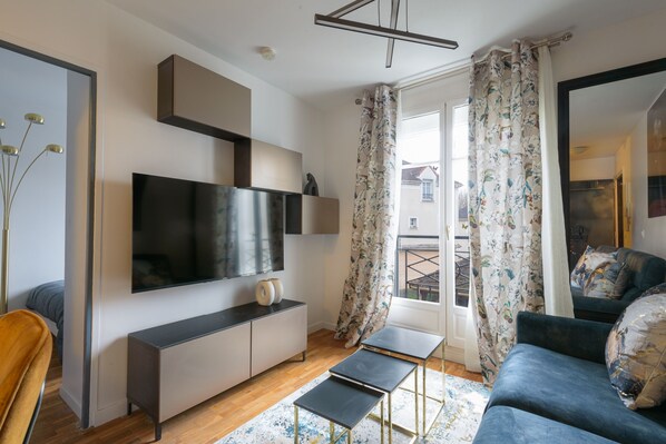 Una sala de estar moderna con un televisor de pantalla plana, un sofá, una mesa de centro y una mesita auxiliar.
