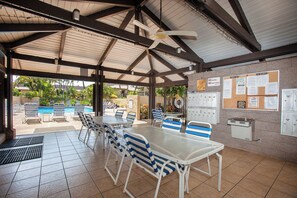 Un espace extérieur abrité comprenant une piscine, des chaises longues et une table avec des chaises.