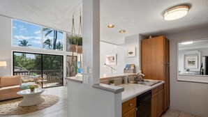 Een moderne keuken met een groot raam, houten kastjes en een eethoek met een ronde tafel en stoelen.