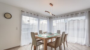 Un coin repas avec une table en bois, six chaises et une horloge au mur.