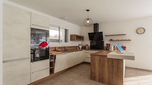 Une cuisine moderne dotée d’un îlot central, de meubles en bois et d’un four encastré.